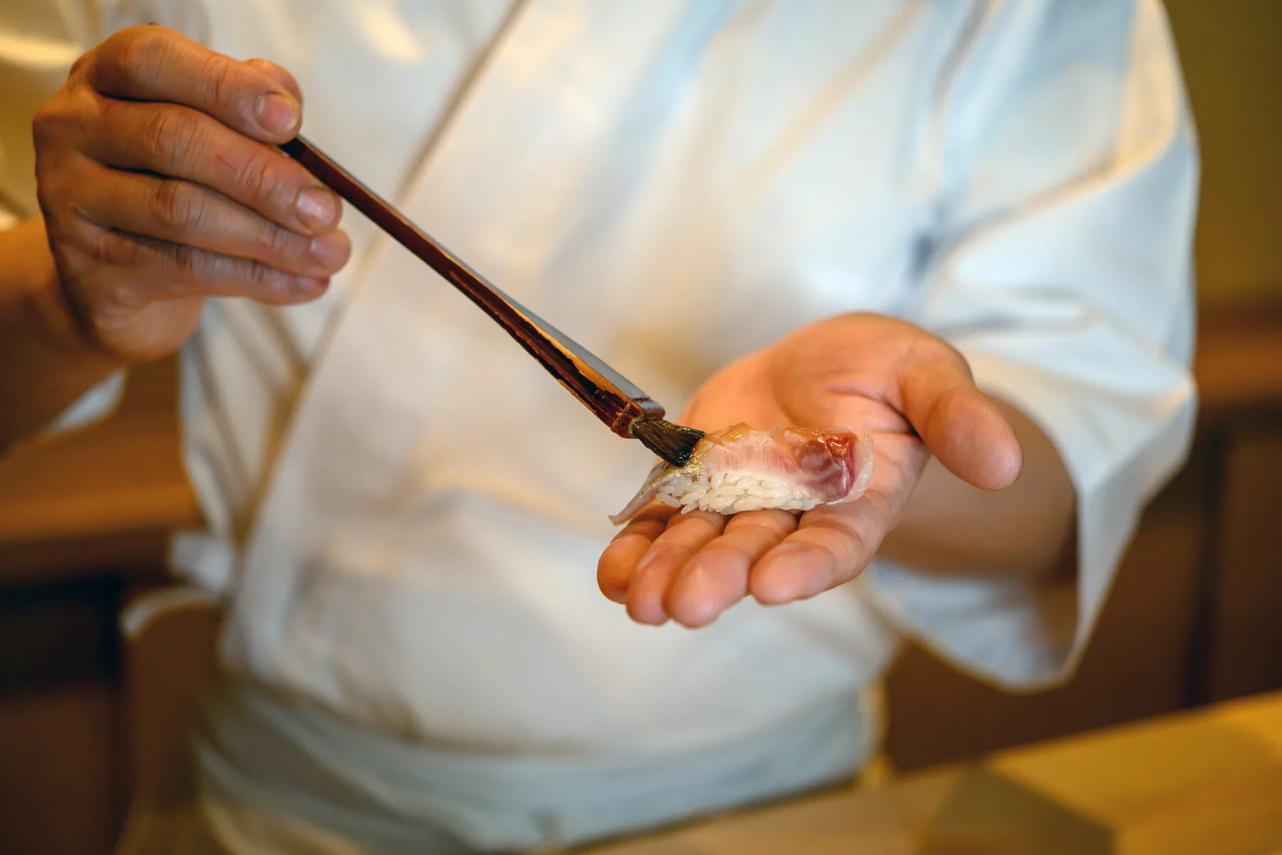 Chef Shion Uino preparing sushi at his counter, emphasizing the personal and focused nature of the dining experience.