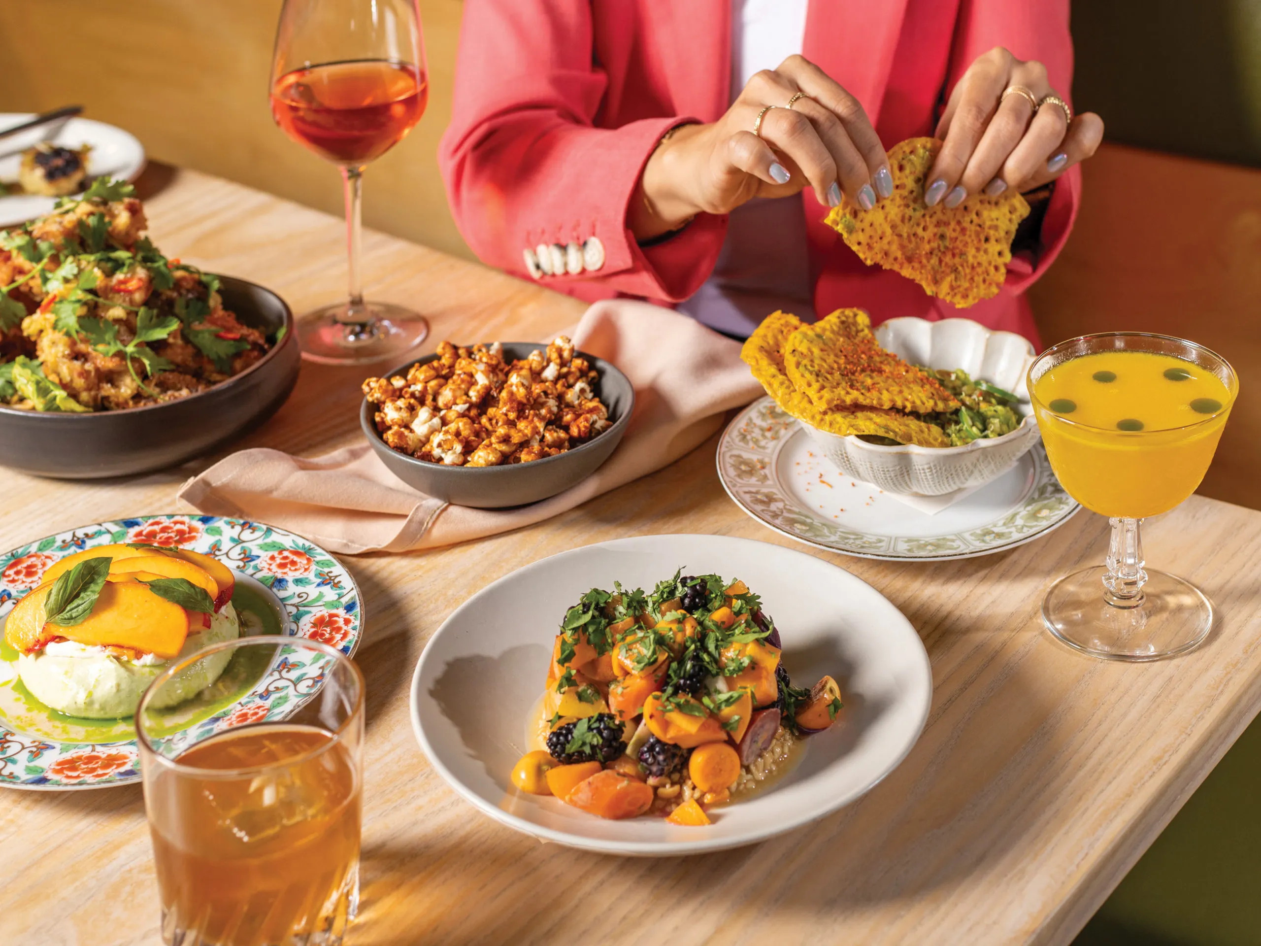 Chefs Ni and Anna Nguyen stand in their kitchen with a spread of Vietnamese dishes on a wood table.