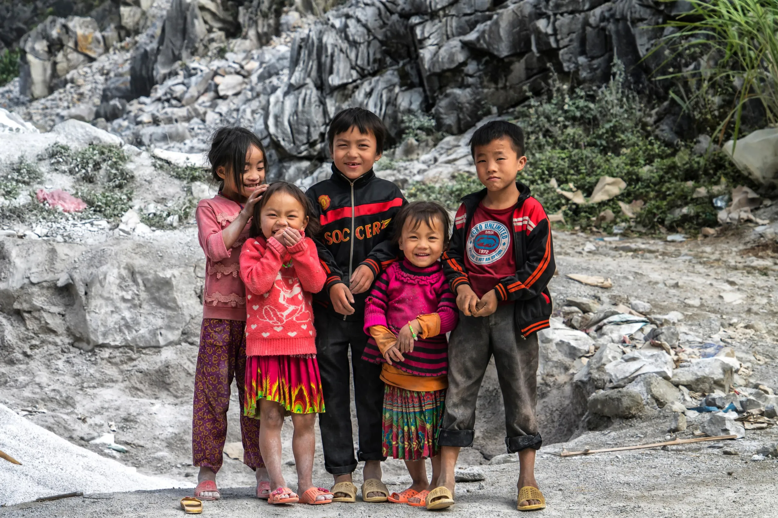 Children playing in the dramatic mountain landscape of Ha Giang province, a remote area perfect for adventurous travel in Vietnam.