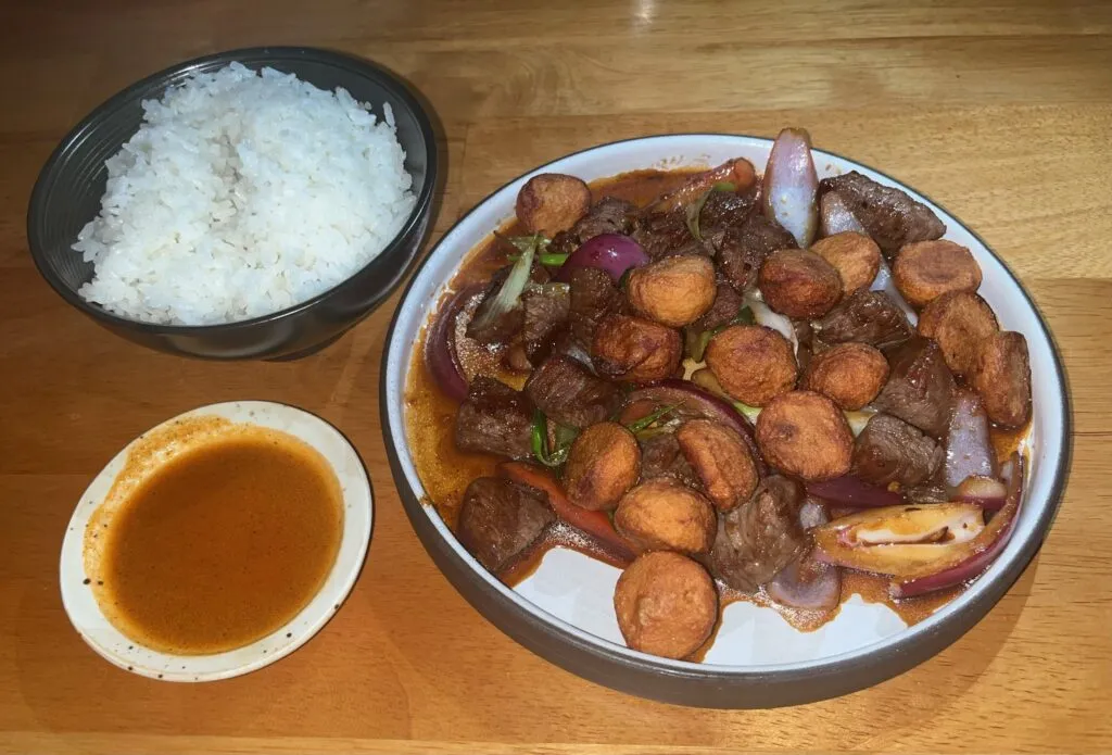 Classic Peruvian Lomo Saltado with beef, vegetables, and sauce over rice
