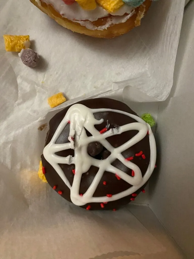 Close-up of a Voodoo Doughnut with a pentagram design, showcasing Austin's unique food scene.