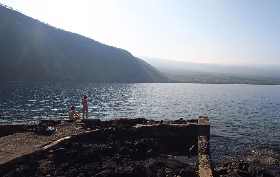 Concrete sea wall with snorkelers on it, at Captain Cook Monument.