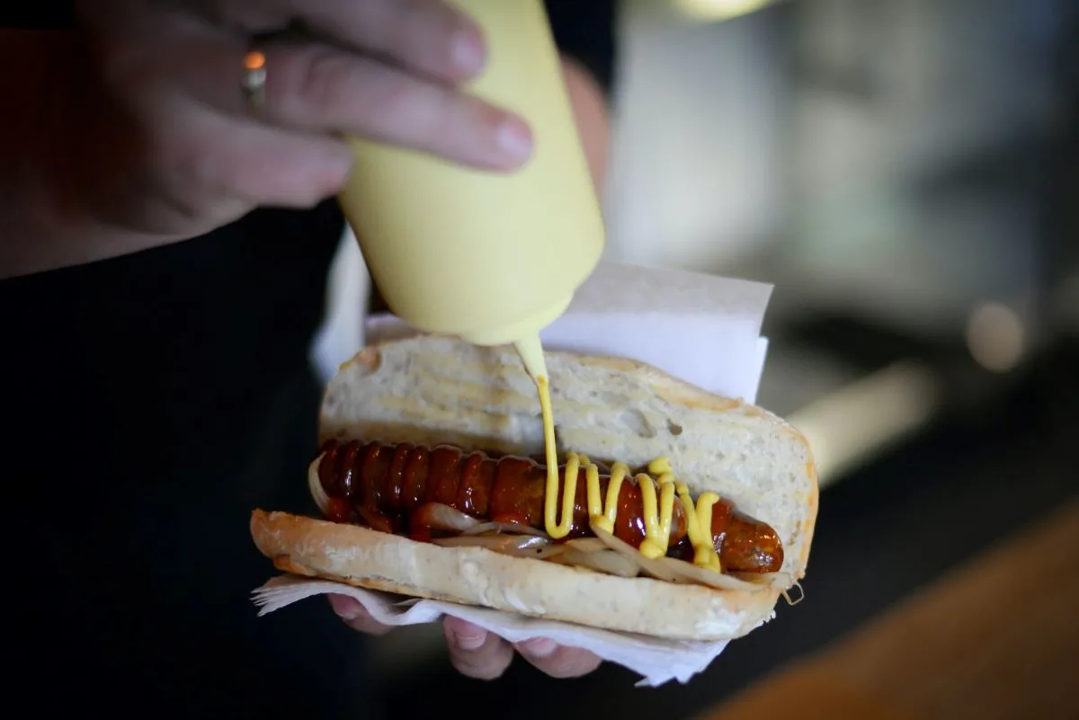 Cook preparing a delicious hot dog, a quintessential famous food in New York street eat.