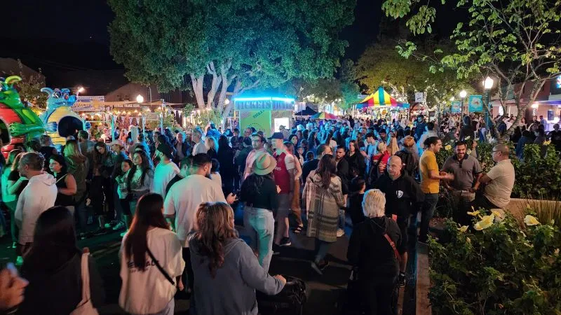 Crowds enjoying carnival rides and food at Montrose Oktoberfest community celebration