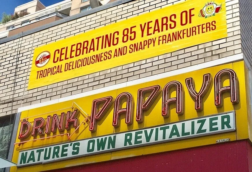 Distinct yellow and red sign for Papaya Dog, an iconic street food stand among famous places to eat in New York