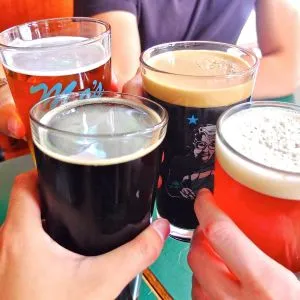 Four hands raise pints of Rogue beer in a toast during a Portland beer tour.