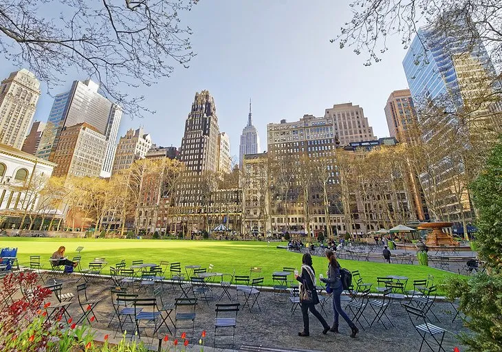 Green lawns and trees in Bryant Park with surrounding skyscrapers in New York City.