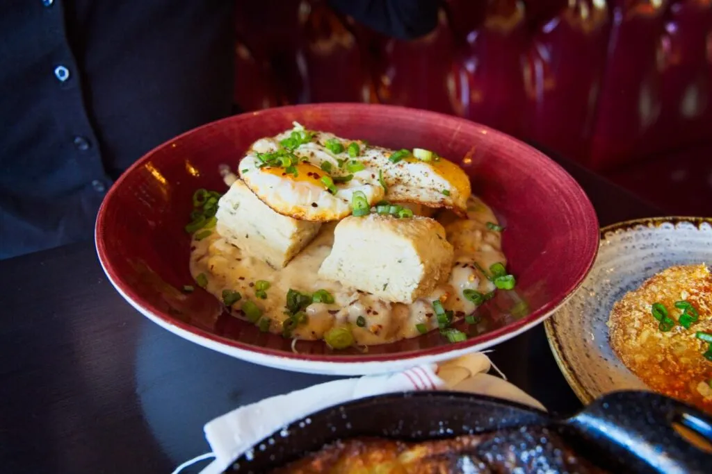 Herb biscuits with sausage gravy topped with a perfectly fried egg at Bar Dough, offering elevated brunch in Denver's Highlands.