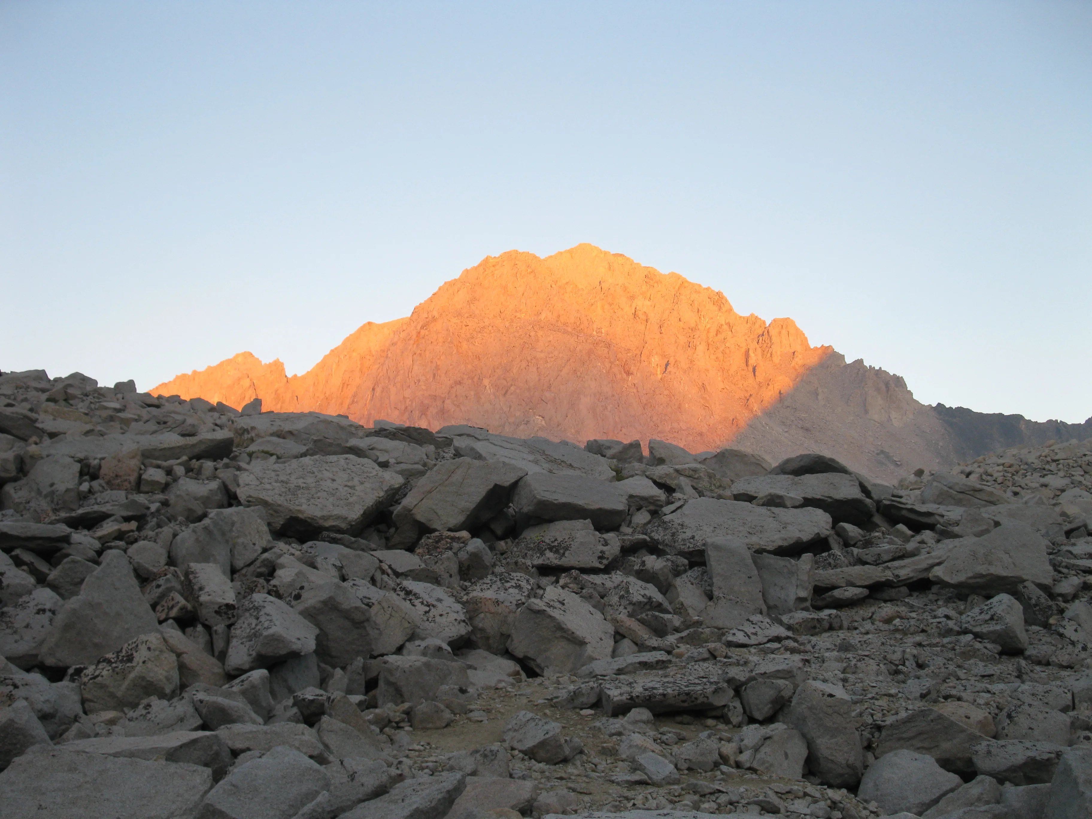 Hiker standing on a rocky ridge with views of mountains and valleys