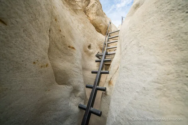 Hikers navigating a narrow slot canyon trail with rocky walls