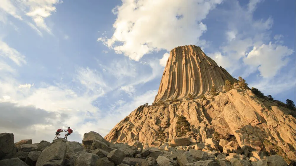 Hikers scaling rocks in front of Devils Tower National Monument