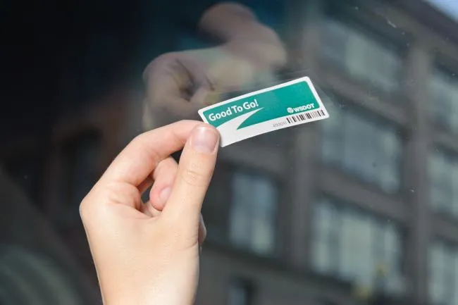 Installing a Good To Go sticker pass on a car windshield for toll payment in Washington State.