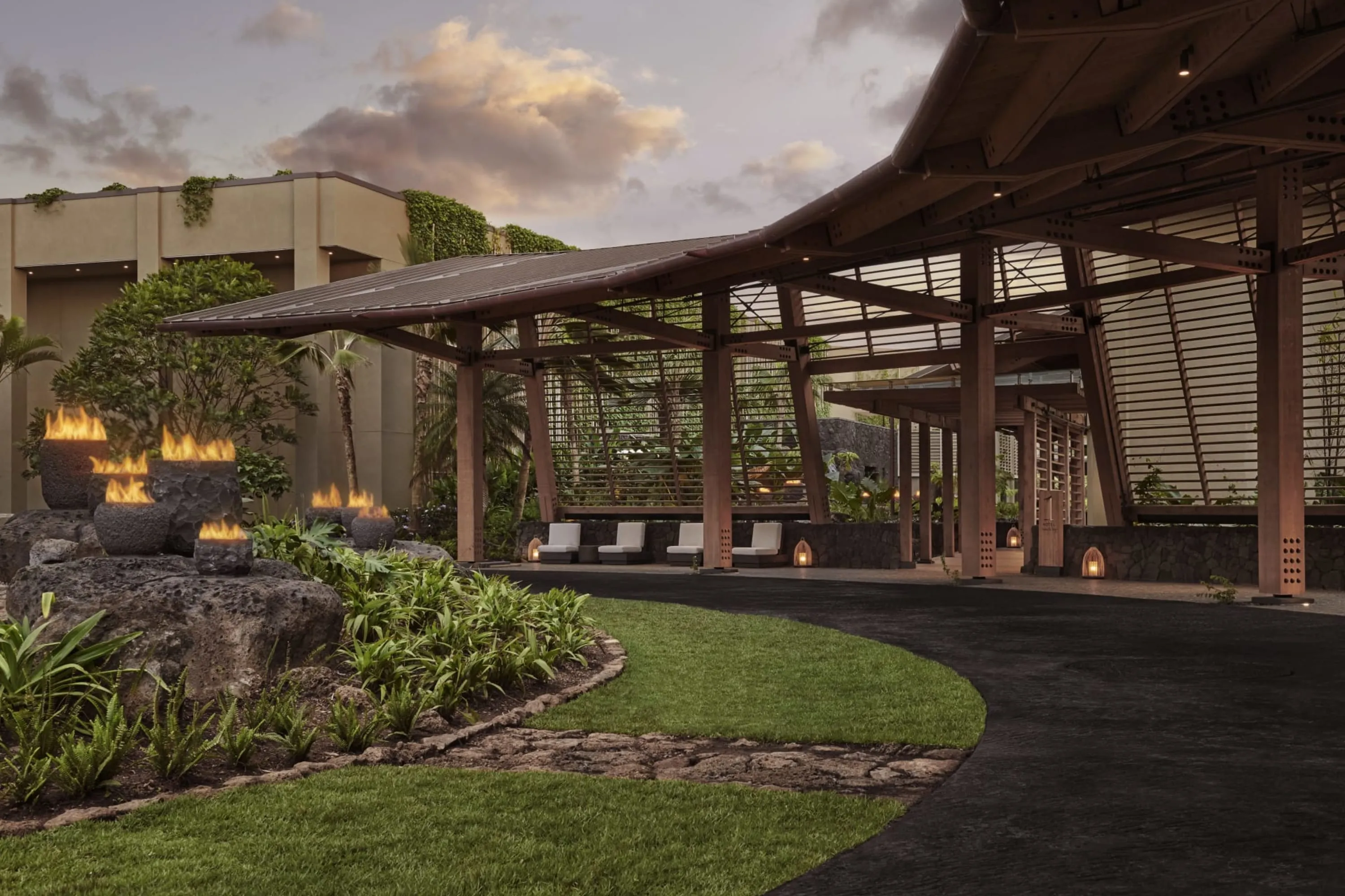Island-themed entrance with lots of woodwork juxtaposed with a small garden lit by a series of firepits