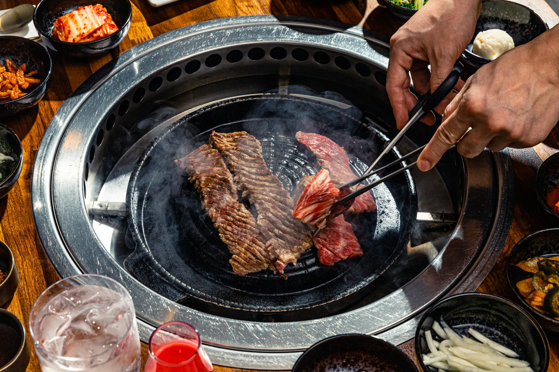 Korean short ribs (galbi) cooking on a tabletop grill at Yoon Haeundae Galbi, showing the scoring on the meat.