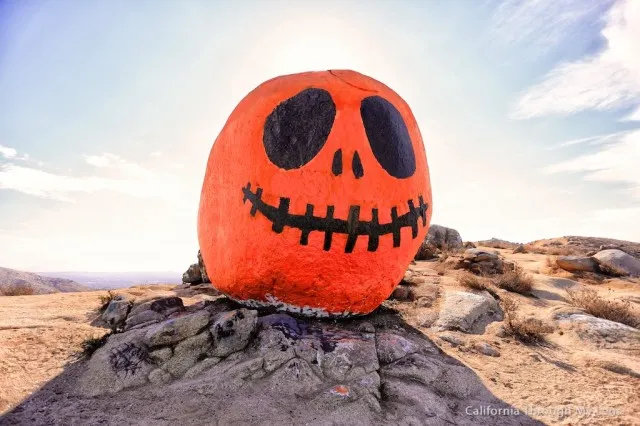 Large rock painted to look like a jack-o'-lantern on a hill