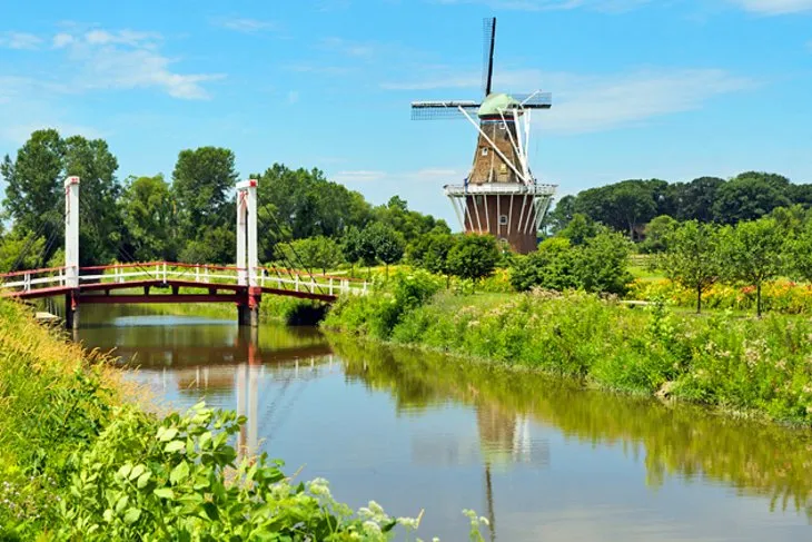 Large, traditional Dutch windmill on a green island surrounded by water
