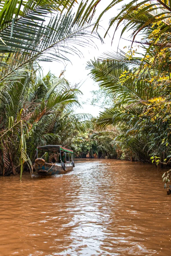 Local boat navigating the waterways of the Mekong Delta while Backpacking Through Vietnam