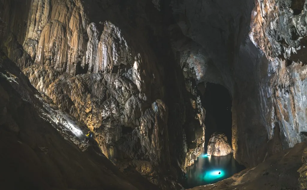 Majestic interior of Son Doong Cave in Vietnam with illuminated sections showcasing its vastness.