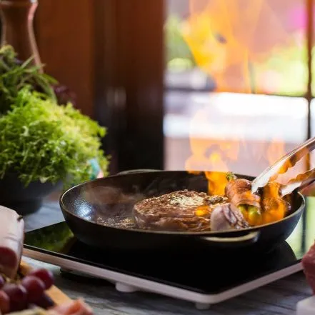 Meat being seared in a pan, typical of techniques taught in French bistro cooking classes in Detroit