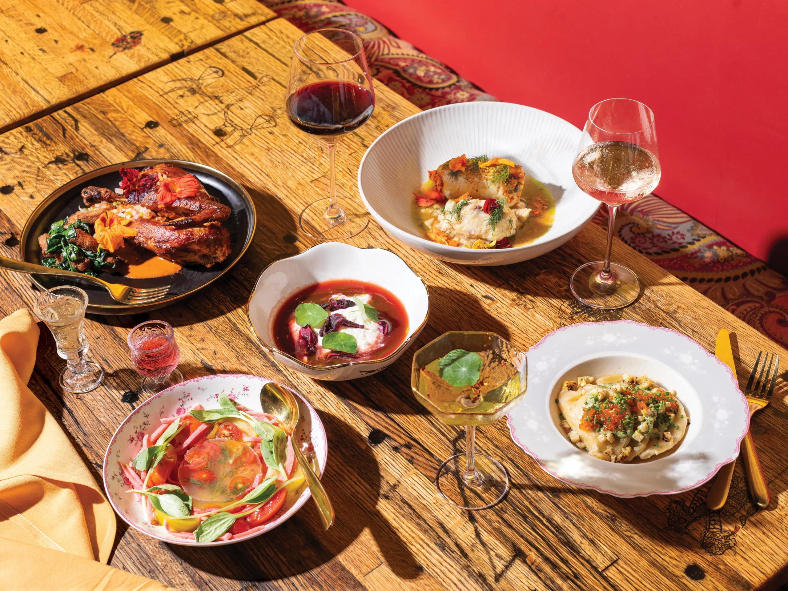 Multiple vibrant dishes are arranged on a rustic wooden table.