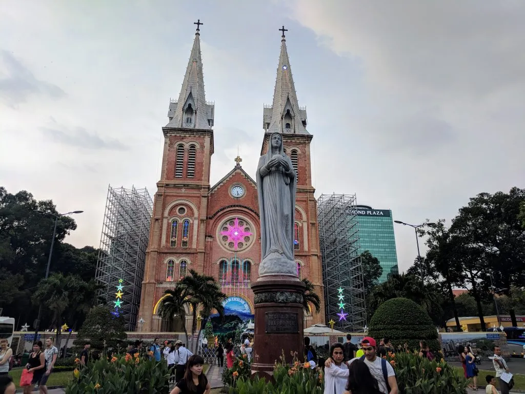 Notre-Dame Cathedral Basilica of Saigon in Ho Chi Minh City, Vietnam, with visitors in the foreground.