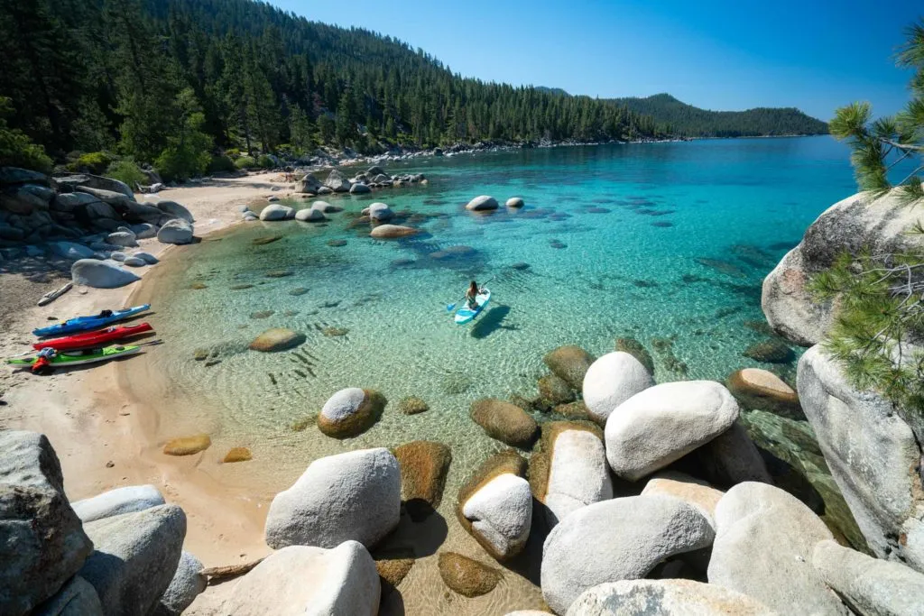 Paddleboarder on the clear waters of Lake Tahoe near granite rocks