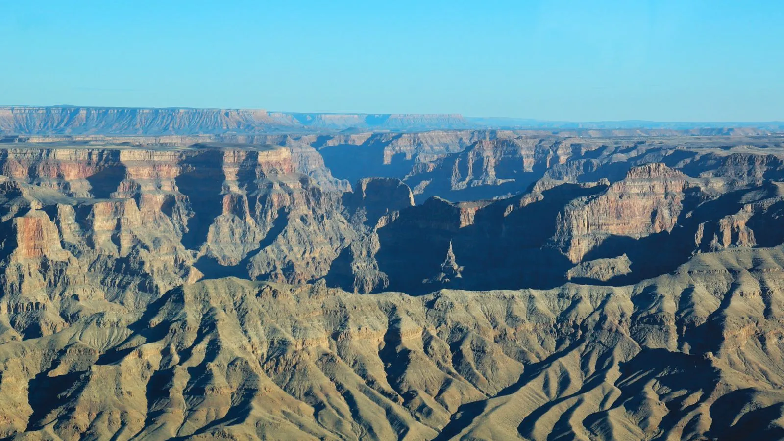 Panoramic aerial view from a helicopter showcasing the breathtaking scale and diverse rock formations of the Grand Canyon West Rim.