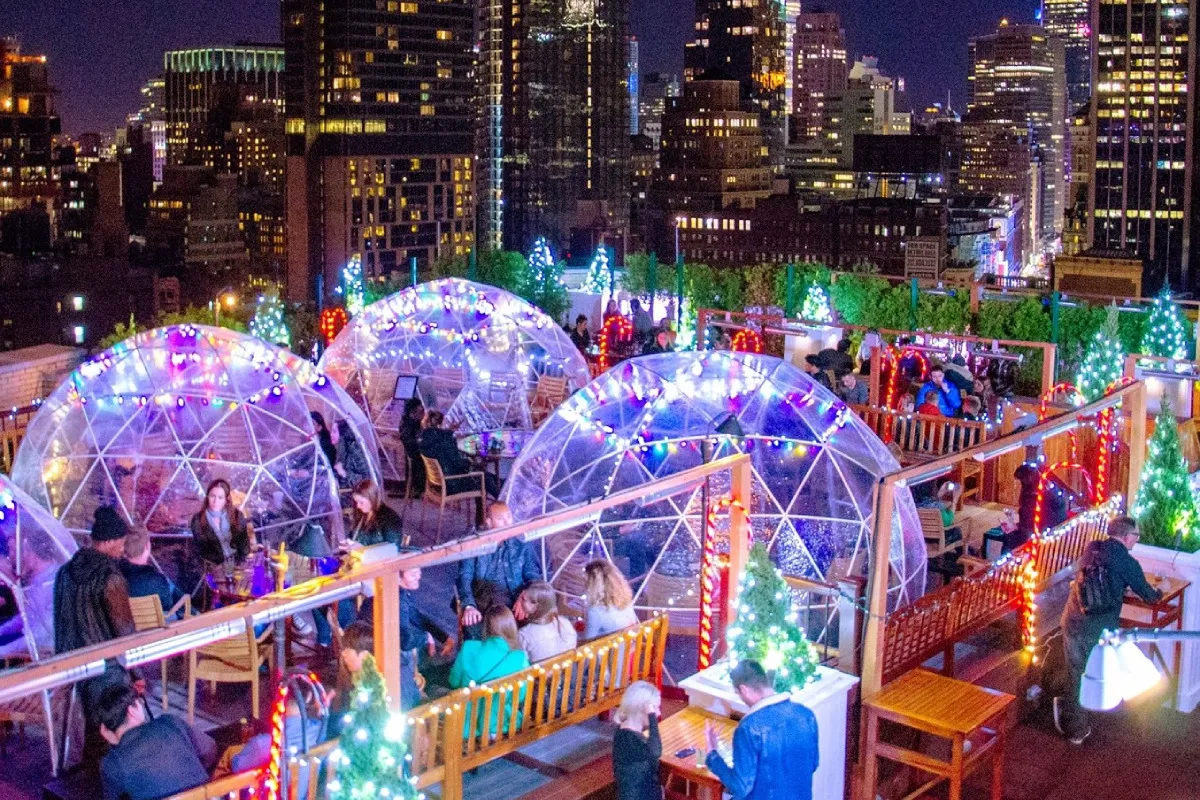 People enjoy outdoor dining in private igloos at 230 Fifth Rooftop Bar, a popular choice for cozy experiences when thinking about what to do in NYC in December.
