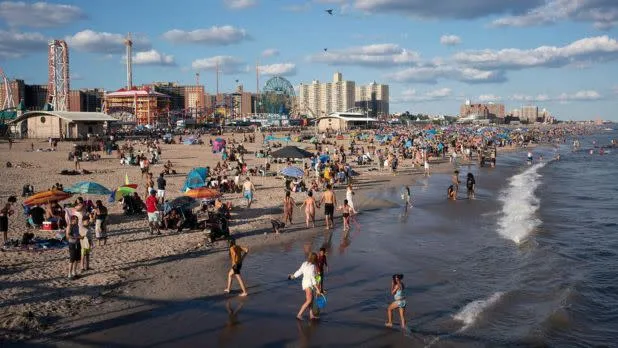 People enjoying the sand and boardwalk at Coney Island Beach in Brooklyn