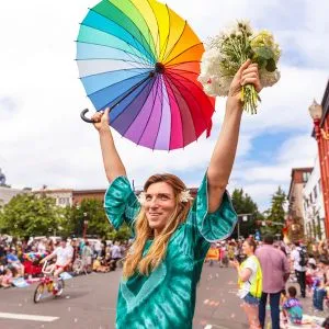 People holding flowers and a rainbow flag during the Portland Pride parade, celebrating diversity and adding to the fun things to do in Oregon