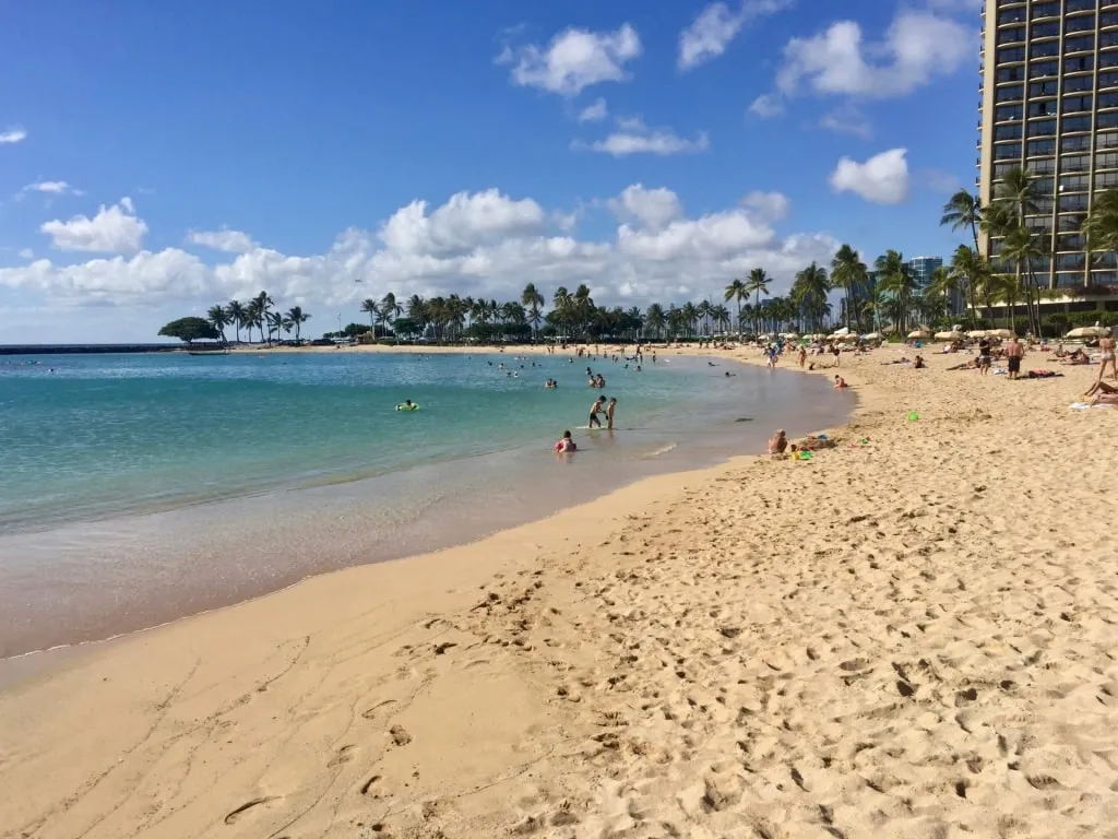People relaxing on the fine, broad sands of Duke’s Beach, a tribute to Duke Kahanamoku, near the Best Beach In Honolulu