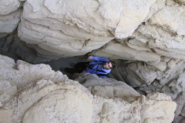 Person walking through a narrow slot canyon with tall, sculpted rock walls