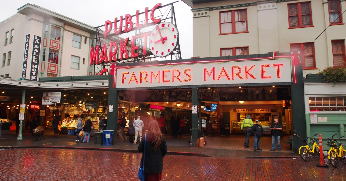 Pike Place Market sign with neon lights against a blue sky