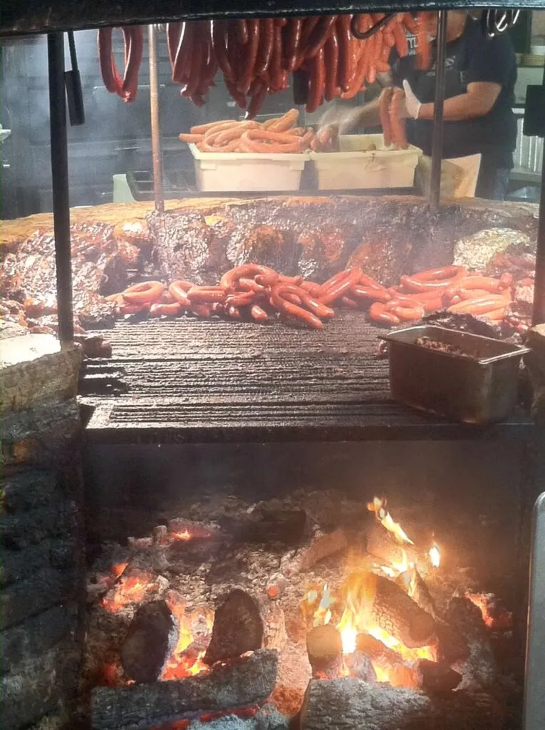Platter of smoked brisket and sausage at Salt Lick BBQ in Texas, a must-try food experience.