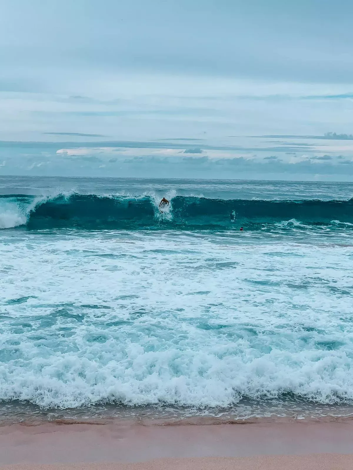 Pro surfers riding a massive wave at Banzai Pipeline, Oahu
