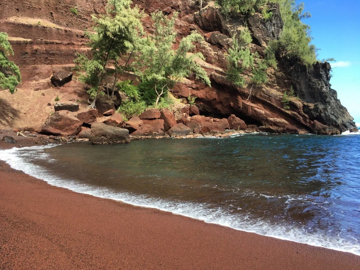 Red sand beach with steep cliffs in Maui, Hawaii.