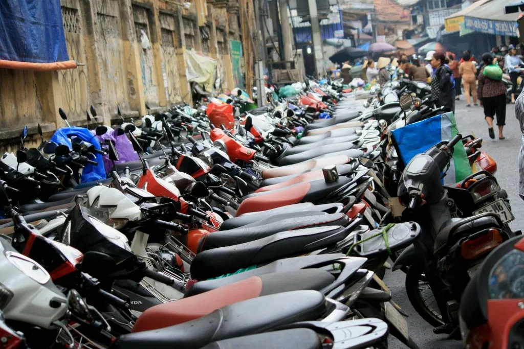 Rows of parked motorbikes crowding a busy street in Hanoi. 