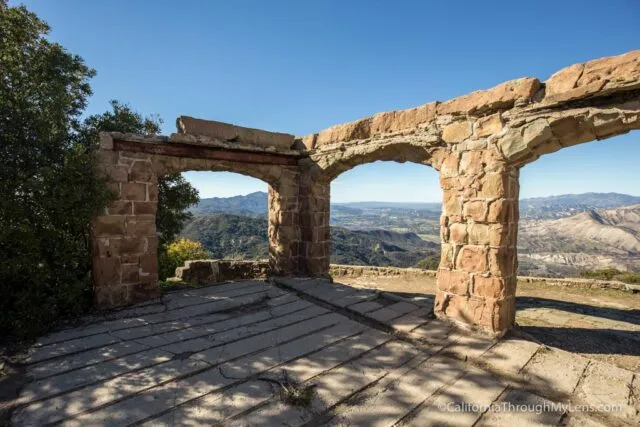 Ruins of stone walls and arches overlooking a valley