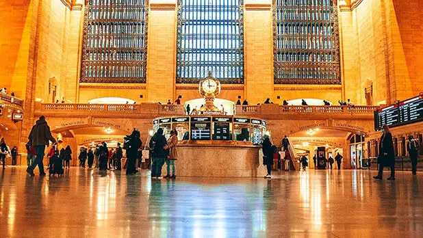 Several people walk through the main concourse of Grand Central Terminal, admiring the architecture
