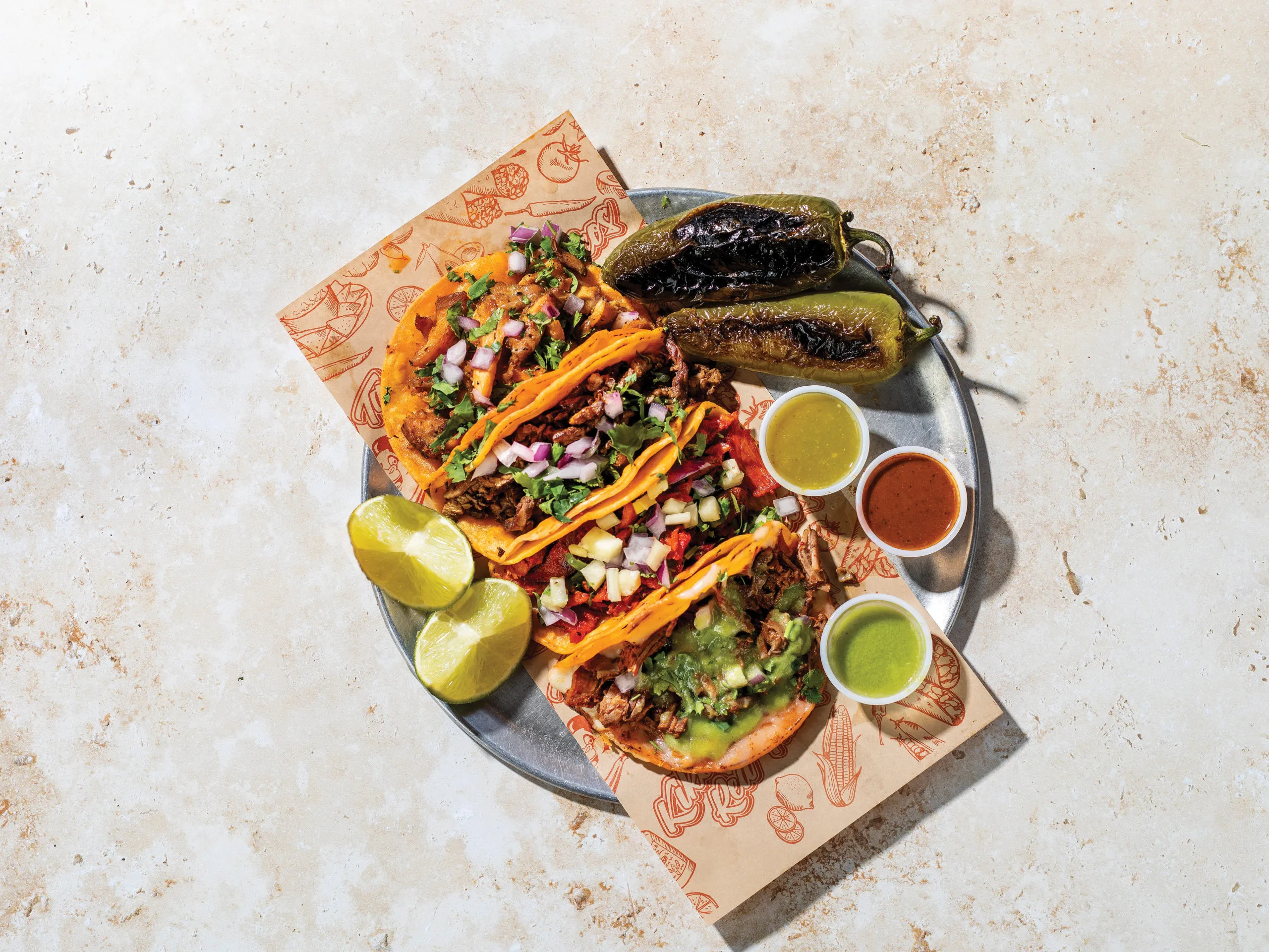 Several red birria tacos are piled high on a plate with consommé.