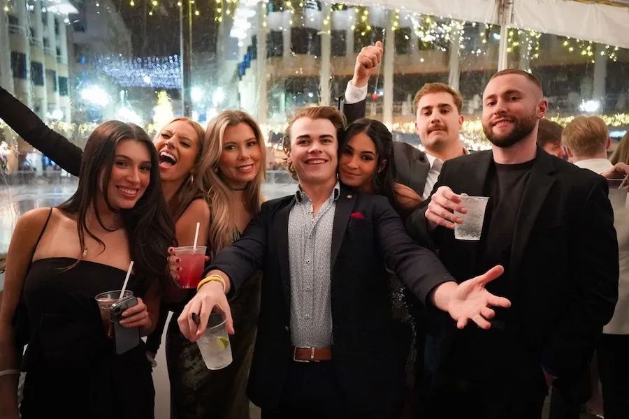Smiling friends at a festive event, representing New Year's Eve celebrations in DC after you Travel To Washington Dc In December.