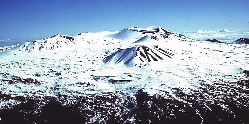 Snow-capped summit of Mauna Kea on the Big Island in winter, with observatories visible.