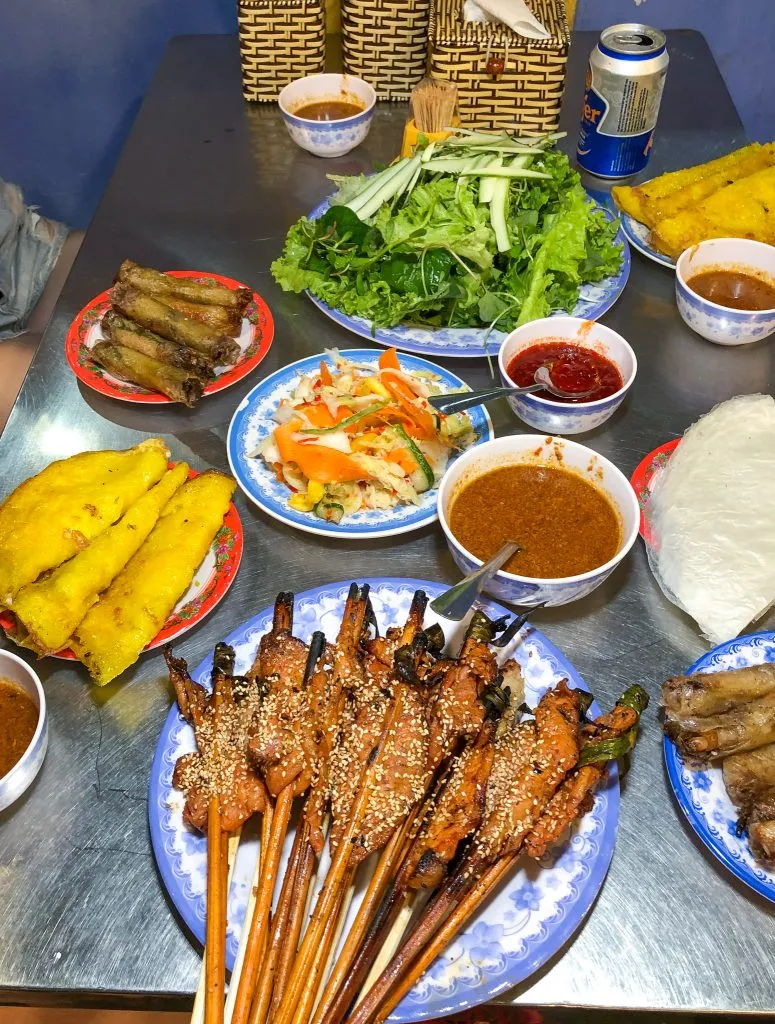 Spread of grilled meats, spring rolls, vegetables, and rice paper wrappers at Bale Well
