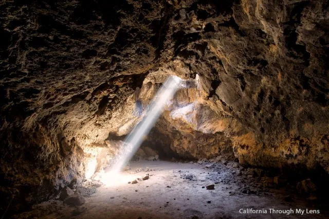 Sunlight beams entering a lava tube cave through openings in the ceiling
