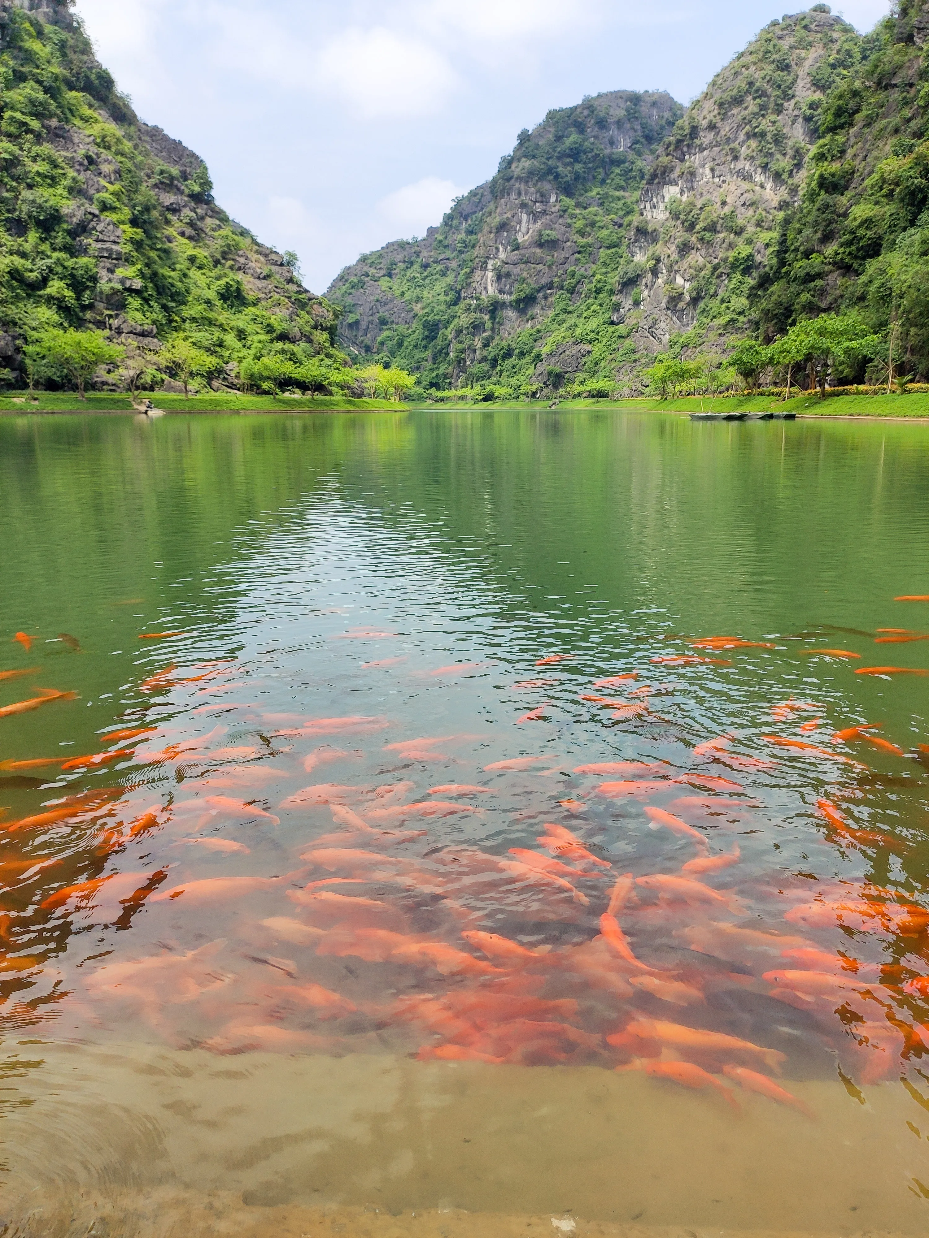The central lake reflecting the surrounding karst mountains at Tuyet Tinh Coc (Am Tien Cave)