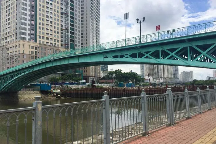 The green-painted arch of the Mong Bridge (Rainbow Bridge) over a river in Saigon