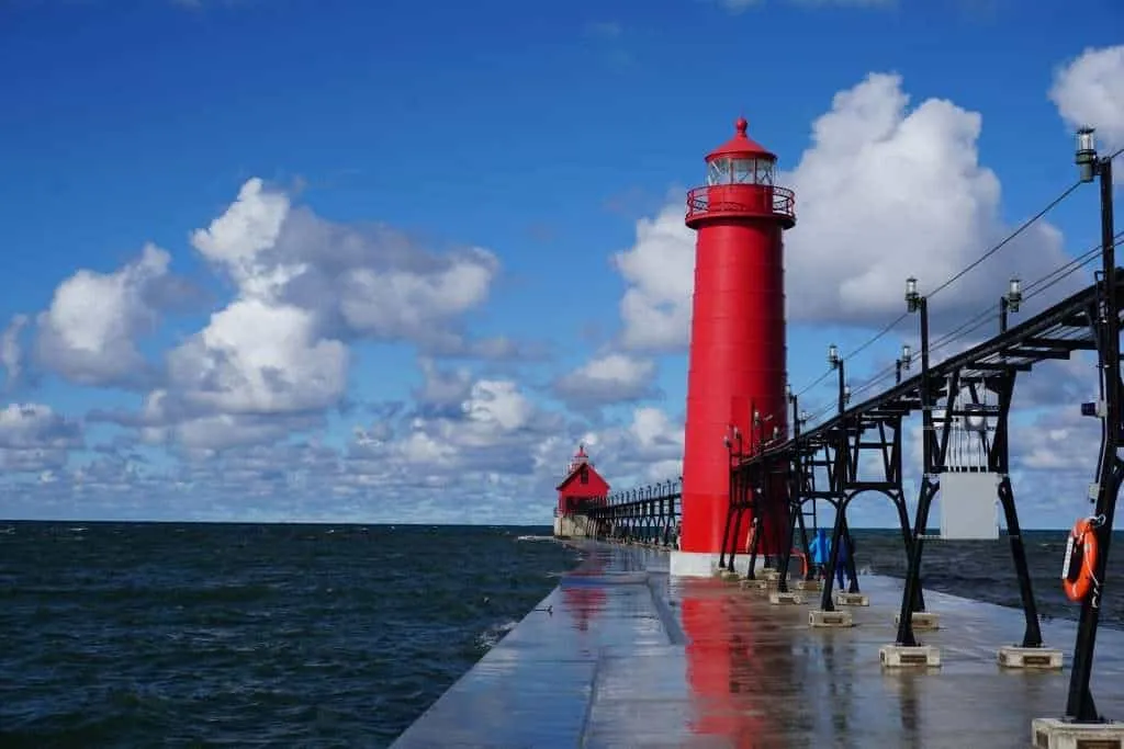 The iconic lighthouse at Grand Haven, Michigan stands proudly at the end of the boardwalk, a central feature of this beloved town and one of the good places to vacation in Michigan.
