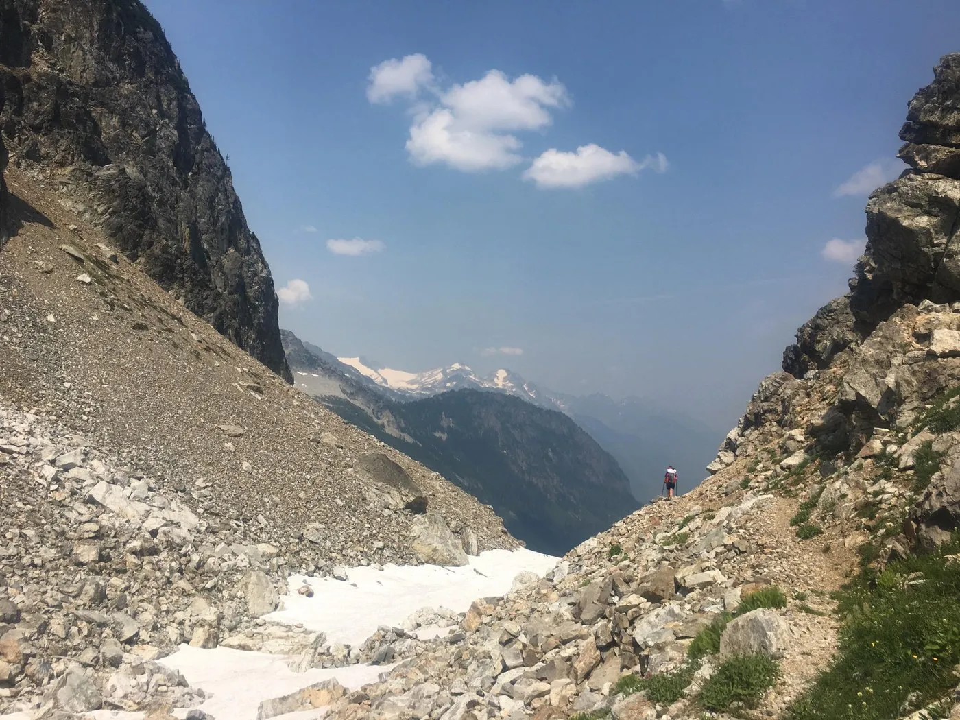 The view from Park Creek Pass opens up to reveal a long lush valley. Steep mountain slopes covered in greenery descend into the valley floor.