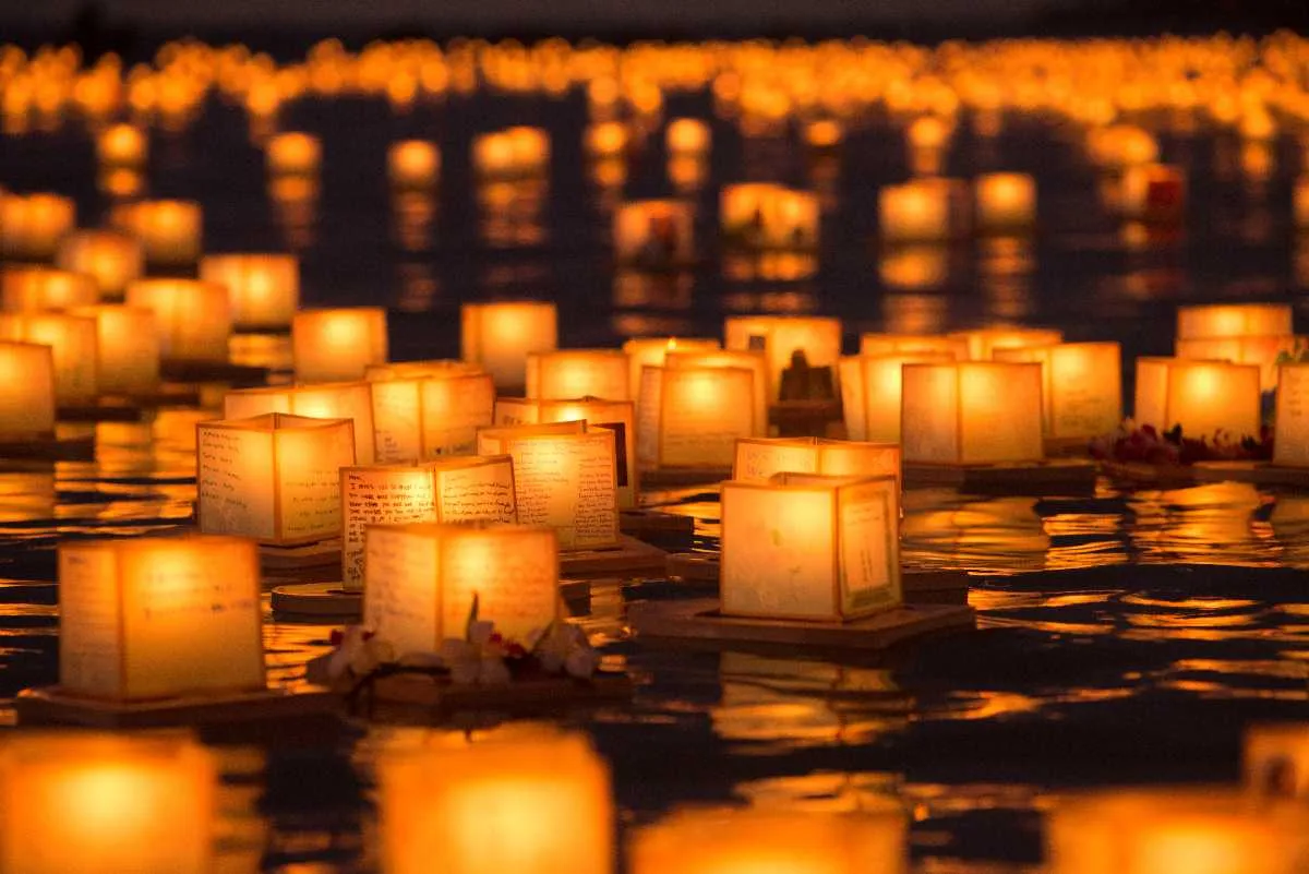 Thousands of lit paper lanterns floating on the water at sunset