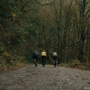 Three cyclists riding on a muddy gravel path in Forest Park, Portland